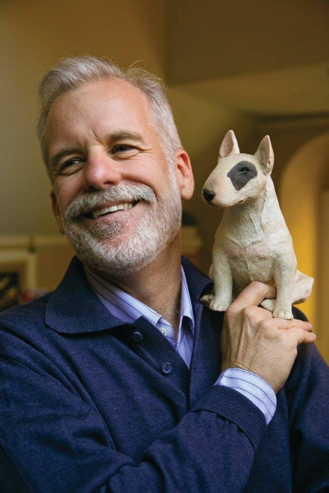 Man holding a small dog statue in a room with a blurred background