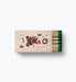 Festive safety matchbox with green tipped matches and colorful holiday illustrations including a bear and wreath by Rifle Paper Co.