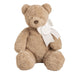 Beige teddy bear with a white bow and mongram tag on a white background