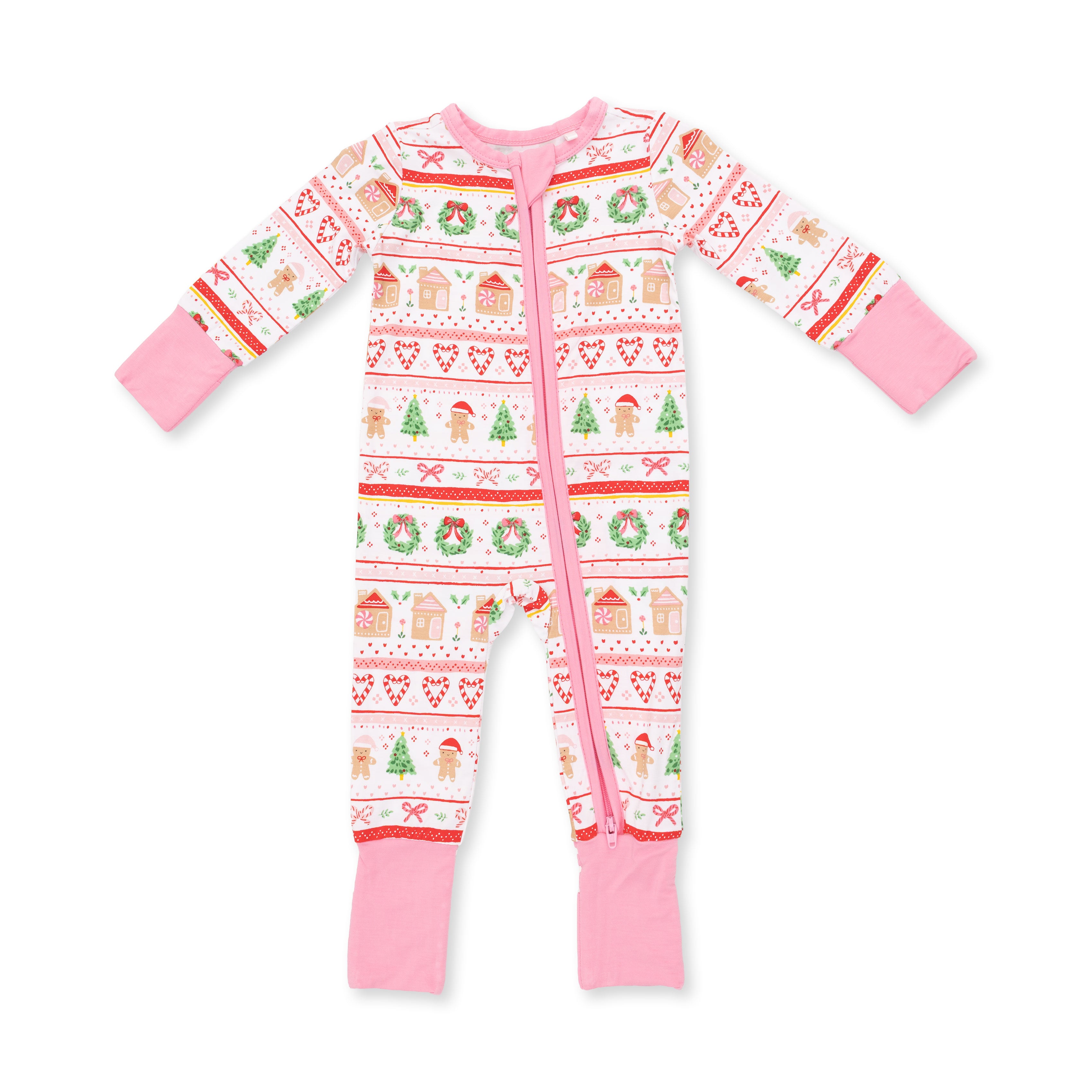 A baby's long-sleeve footed sleeper with a pink and white holiday pattern featuring gingerbread houses, wreaths, and snowman motifs, set against a plain white background.