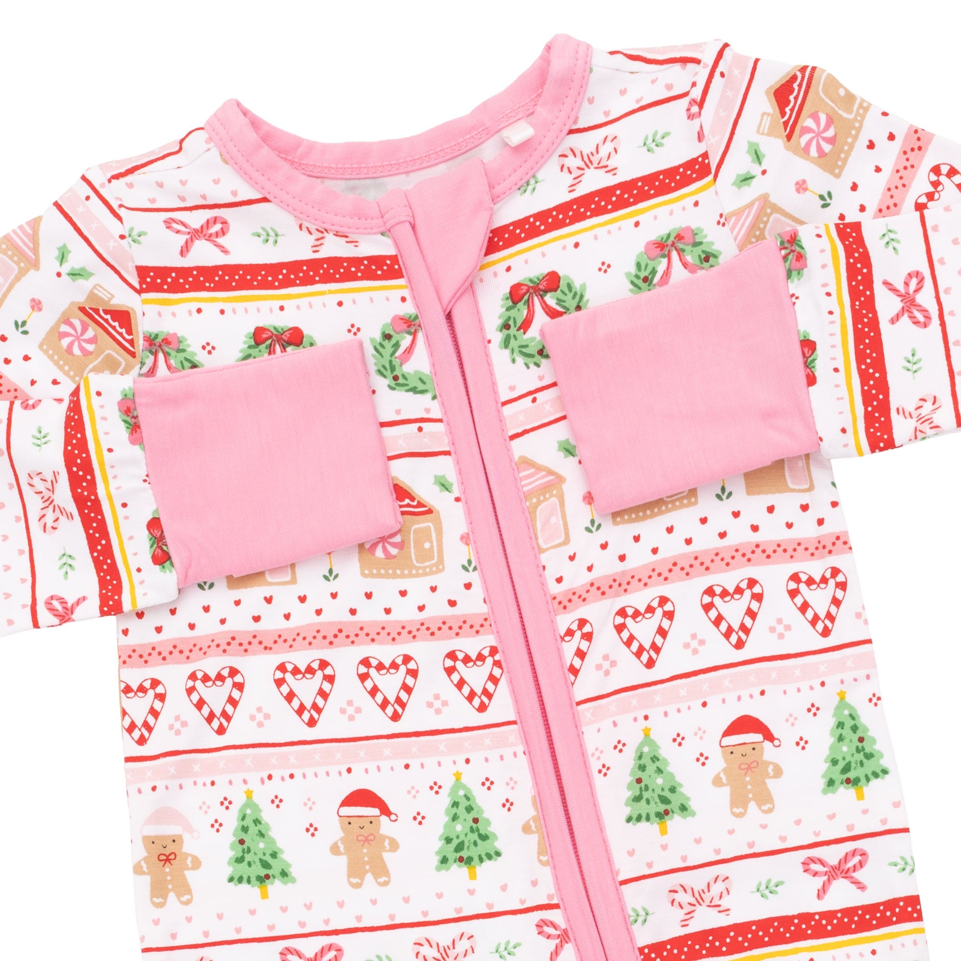 A baby zip-up sleeper with a festive Christmas holiday print, featuring gingerbread men, trees, candy canes, and hearts on a white background with pink trim and pockets.