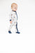 A baby wearing a white footless pajama romper with navy blue stripes and a small teddy bear pattern, standing against a solid white background.