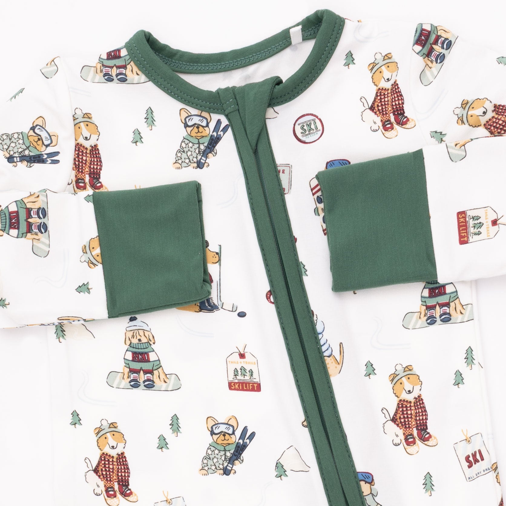Baby onesie with green trim on a winter sports dogs patterned background