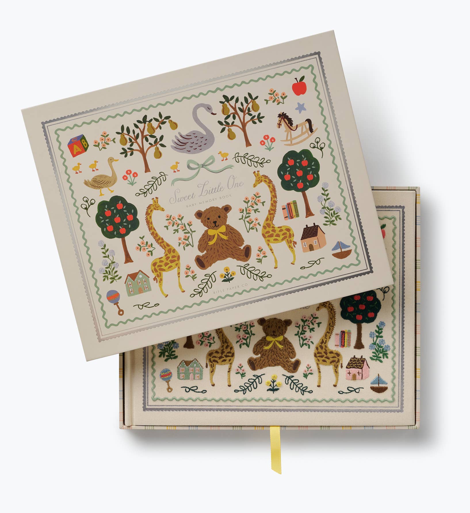 Illustrated keepsake baby book by Rifle Paper Co. with a cream cover featuring a teddy bear giraffes swan flowers trees and colorful nursery motifs