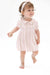 A toddler girl walking barefoot on a white studio background, wearing a light pink short-sleeve dress with vertical floral prints and a matching pink headband.