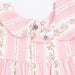 Close-up of a pink floral dress with buttons and ruffled details.