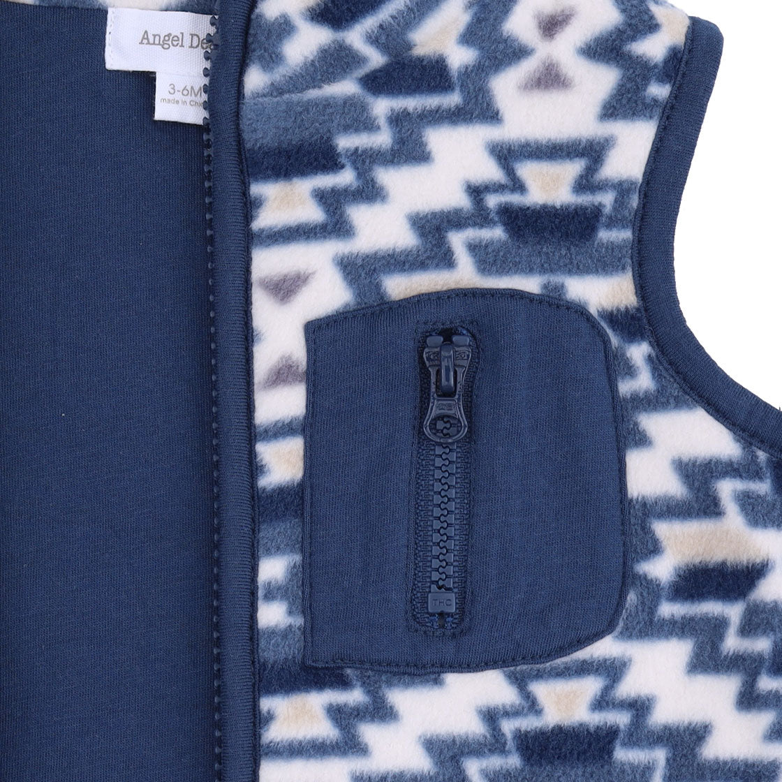 Close-up of a children's zippered fleece vest showing a navy blue zipper, a front zip pocket, and a geometric patterned fleece lining in navy, cream, and tan.
