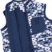 A close-up of a children's fleece vest with a navy blue zipper, solid navy inner panel, and a geometric patterned exterior in cream, navy, and light blue.