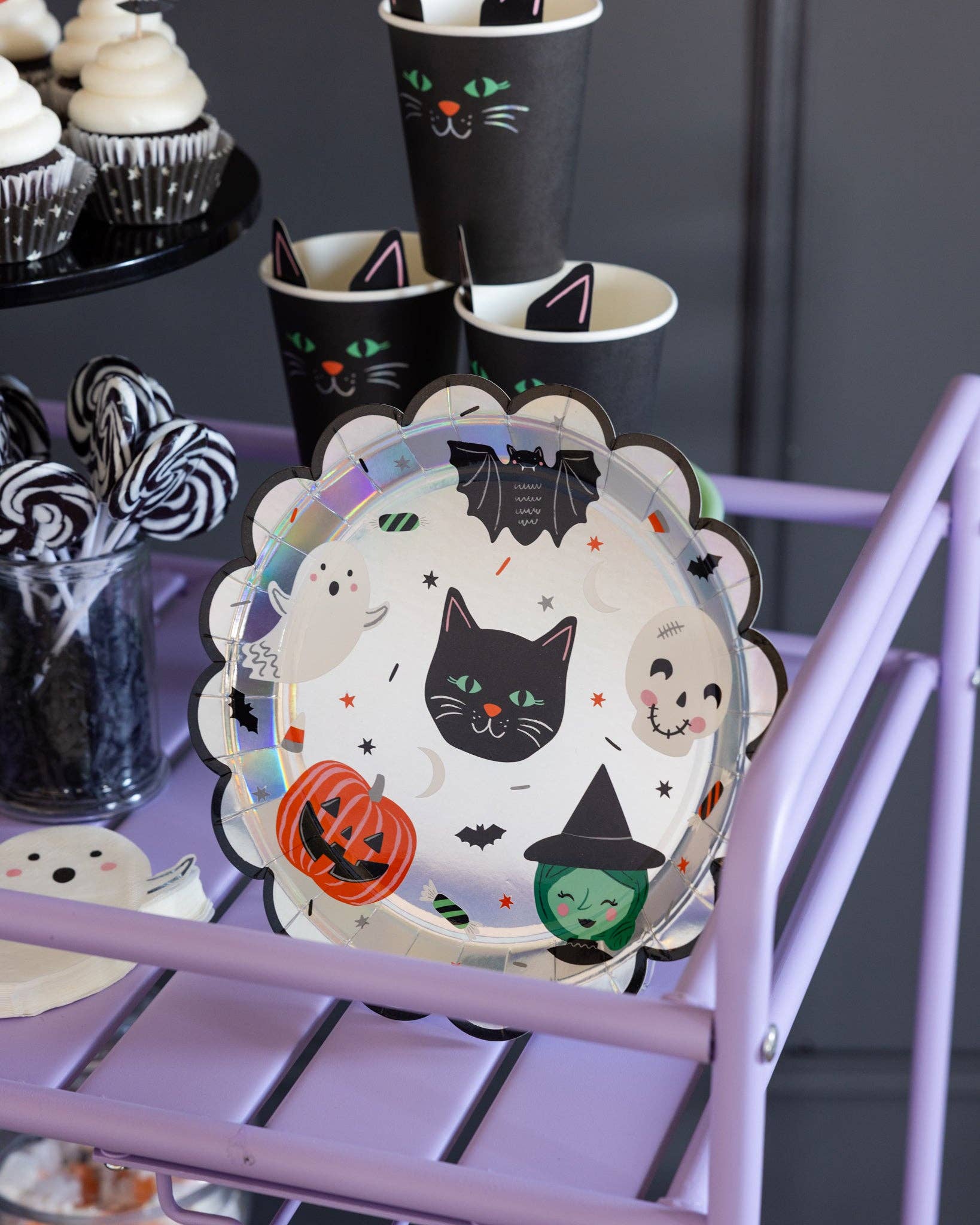 Halloween-themed plate with black cat, ghost, and witch design on a purple stand.
