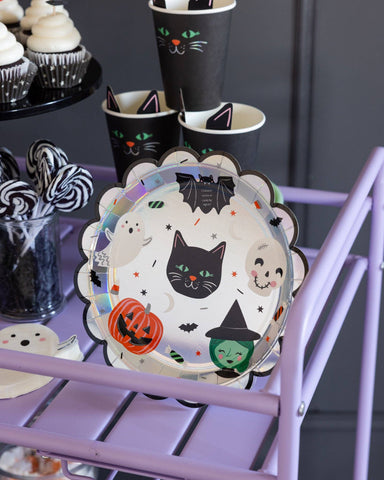 Halloween-themed plate with black cat, ghost, and witch design on a purple stand.
