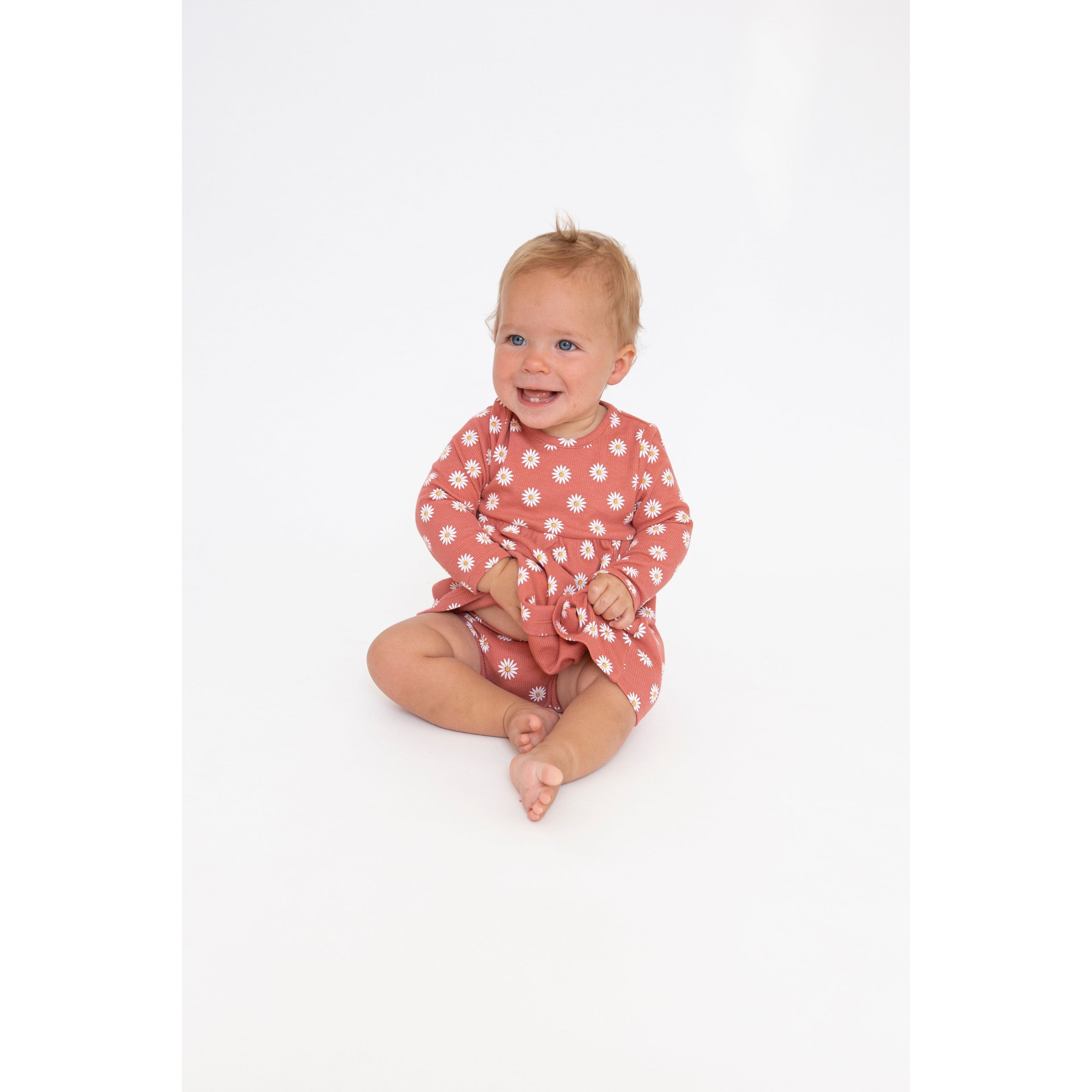 toddler girl wearing dark punch colored long sleeve dress and matching bloomers with white daisy dot print