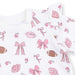 Baby onesie with pink bows and footballs on a white background