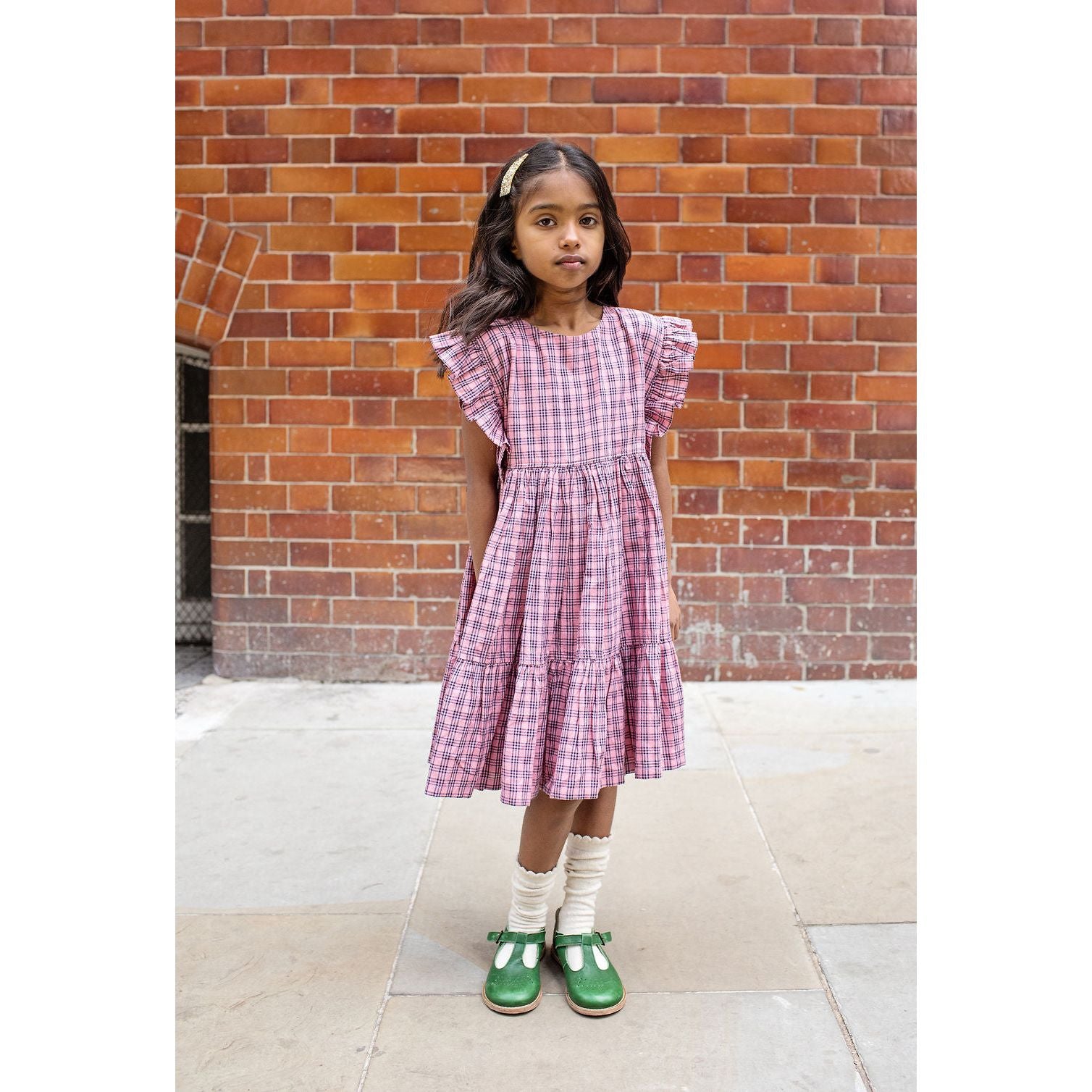 girl wearing pink and navy plaid dress with ruffle sleeve