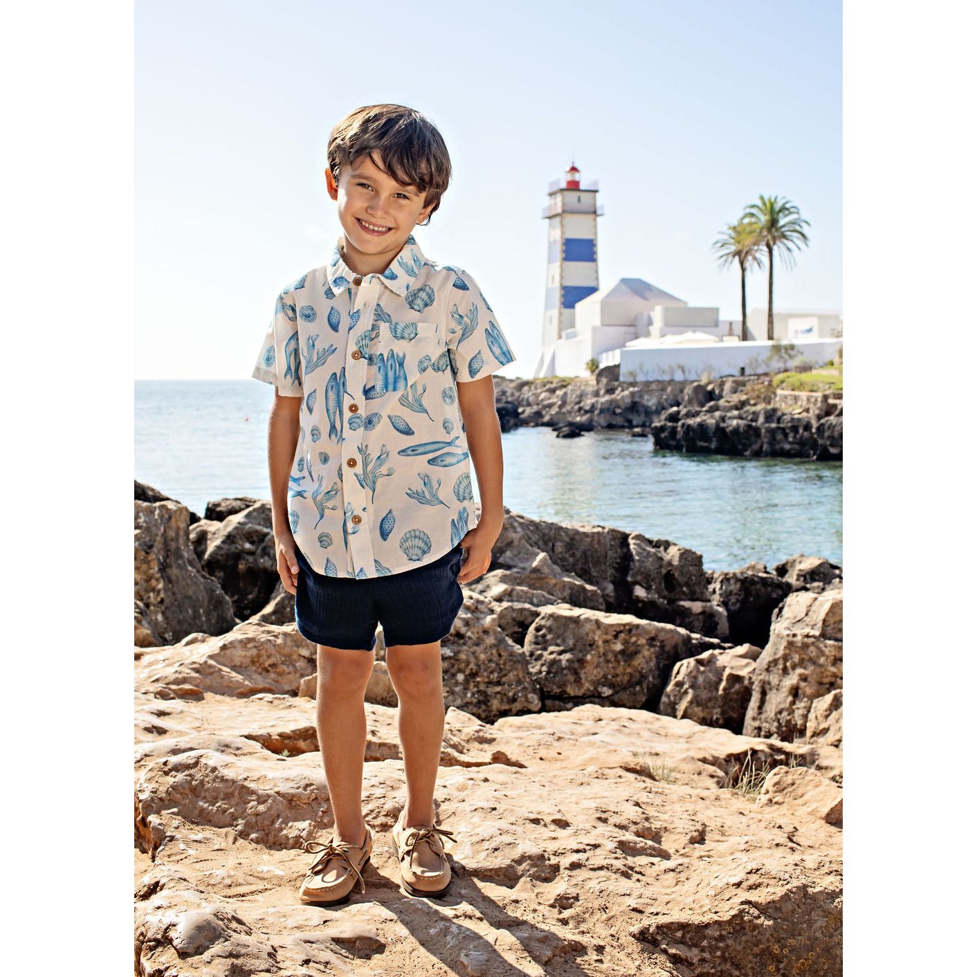 boy wearing white short sleeve collared button down with blue seashell and fish print