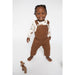 toddler boy wearing brown cordoroy overalls with white onesie underneath