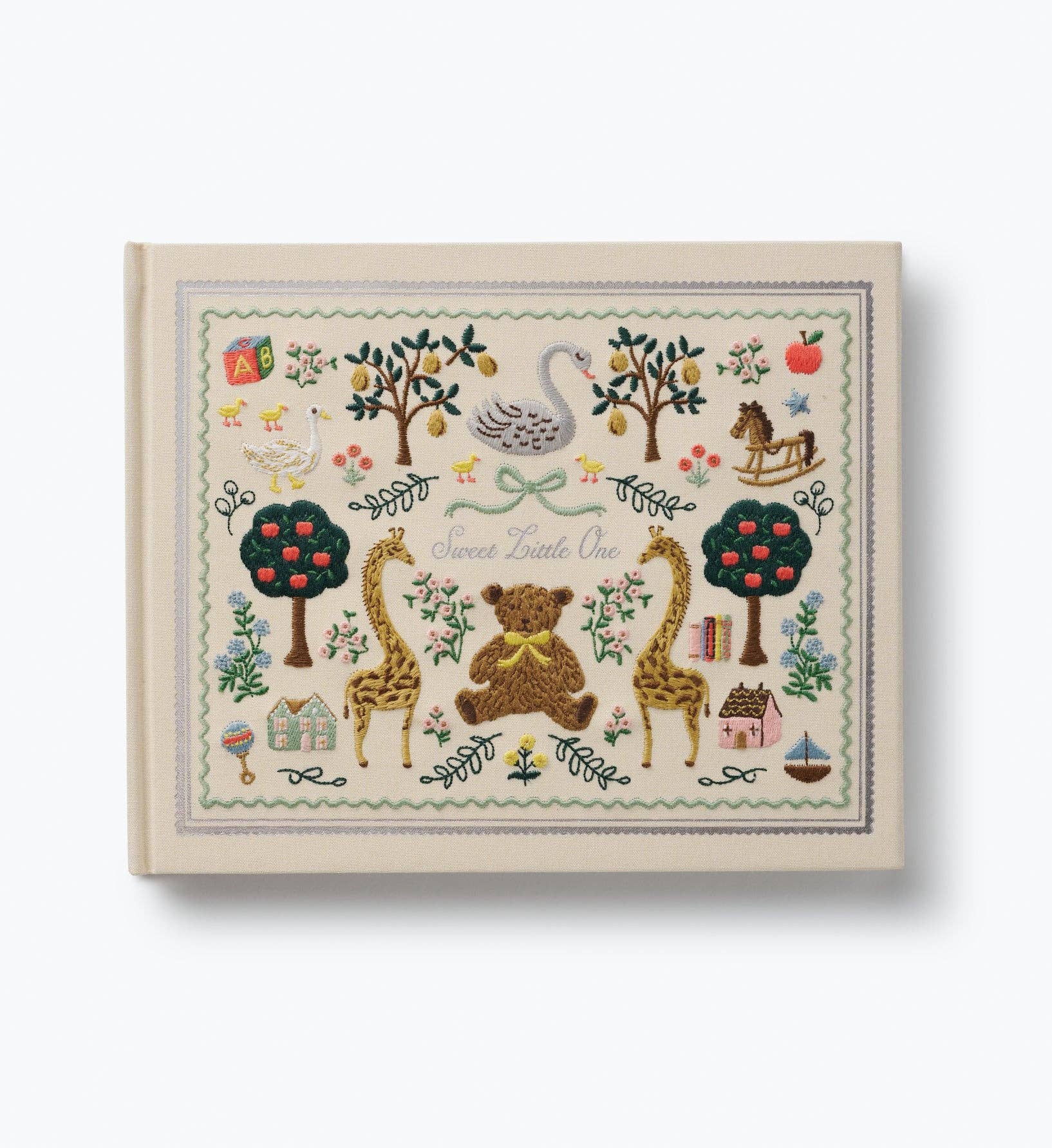 Embroidered baby book cover with giraffes bears swan trees and floral details in a vintage storybook design by Rifle Paper Co.