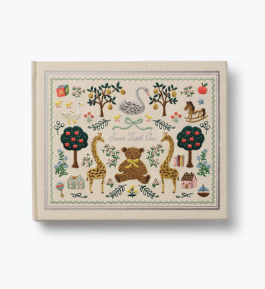 Embroidered baby book cover with giraffes bears swan trees and floral details in a vintage storybook design by Rifle Paper Co.