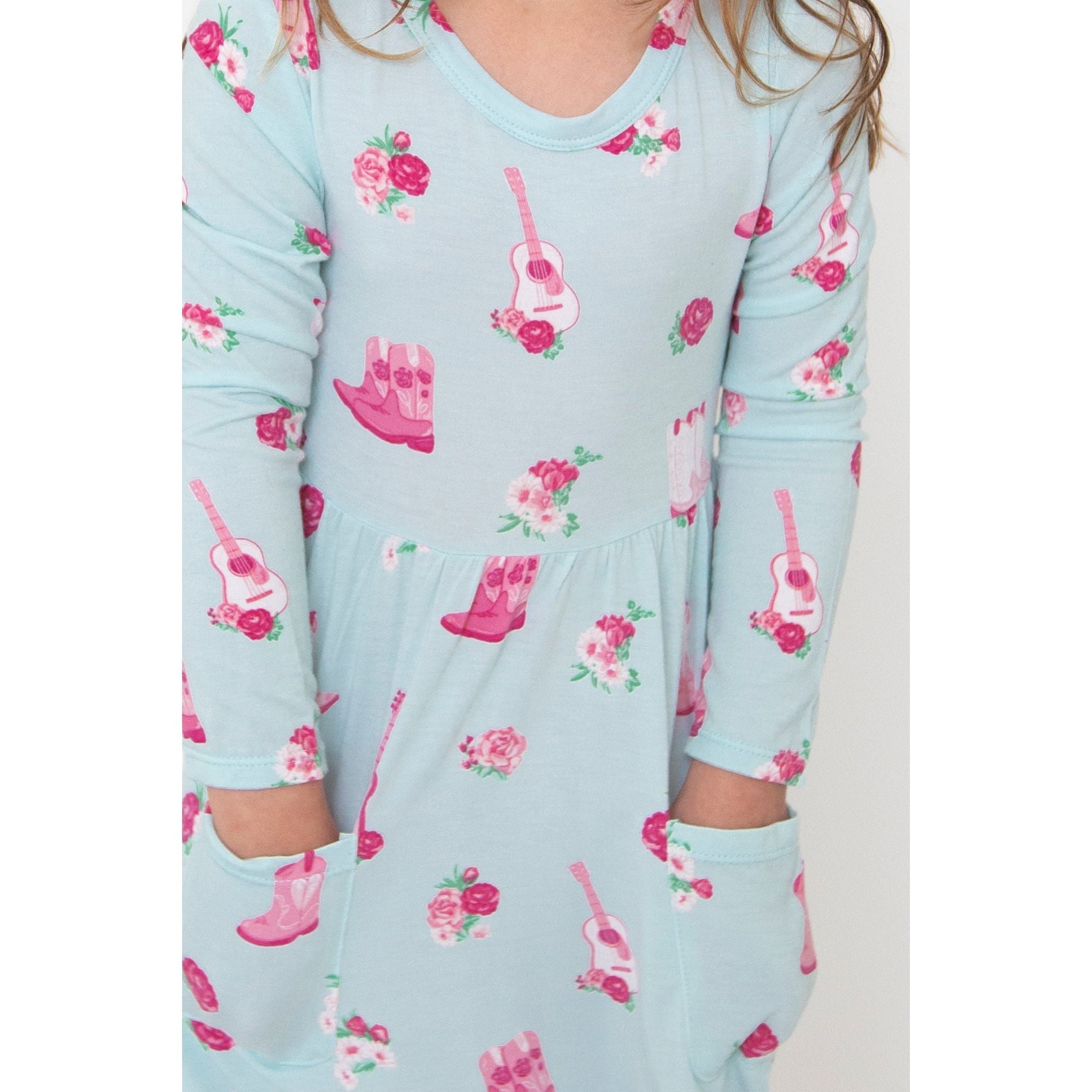 up close of long sleeve blue twirl dress with pink fancy cowgirl print with pockets 