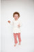 toddler girl wearing white peplum top with punch colored flare pants with daisy dot print