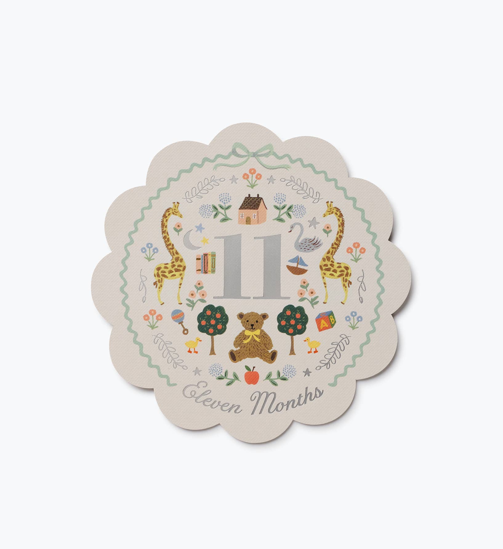 Scalloped illustrated baby milestone card marked Eleven Months with giraffes animals trees flowers and colorful nursery themed artwork by Rifle Paper Co.