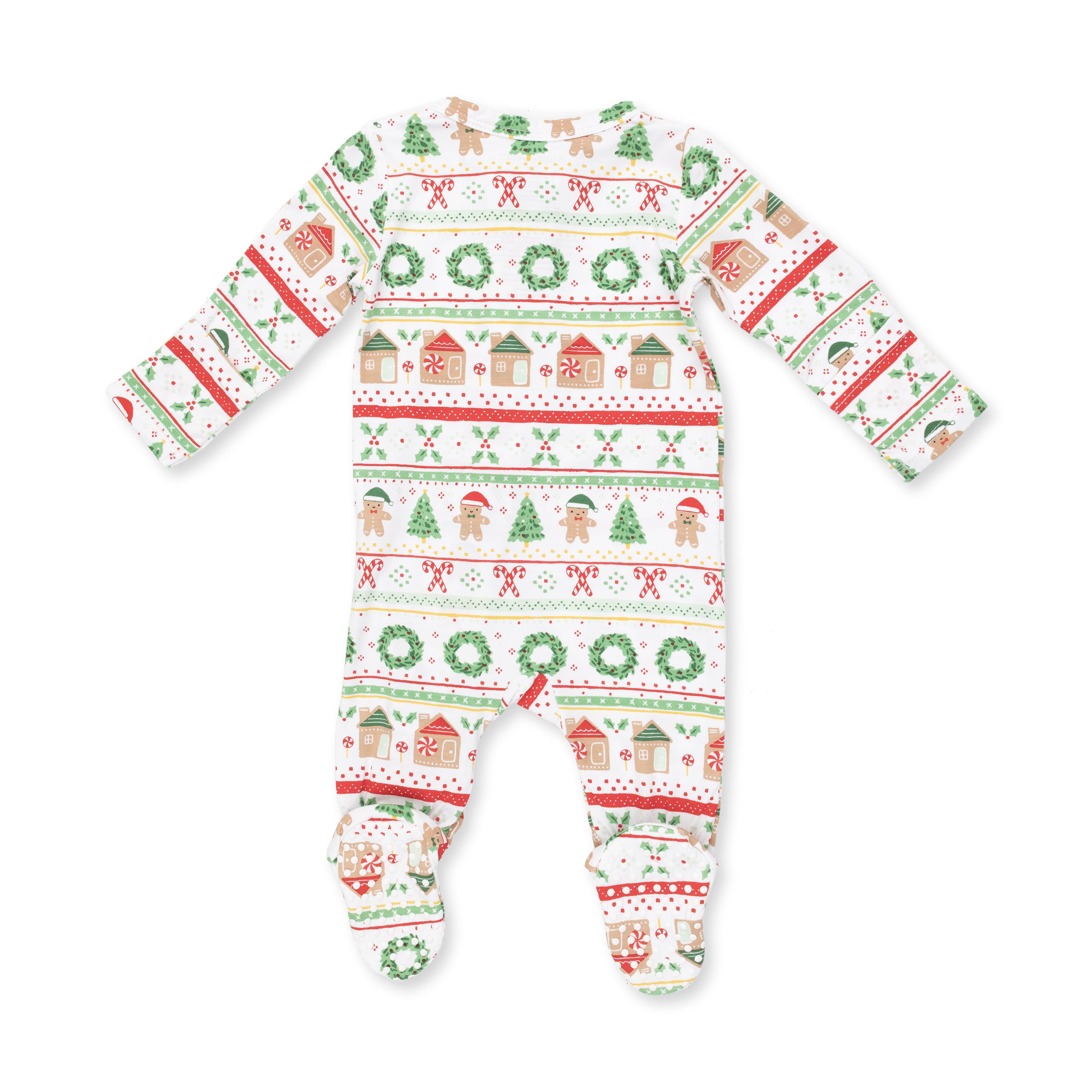 A baby footed sleeper with long sleeves and a festive Christmas pattern featuring green wreaths, gingerbread houses, candy canes, and snowman motifs on a white background.