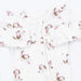 White long-sleeve baby footless sleeper with a front zipper and an all-over print of brown and white puppy illustrations wearing pink bows.