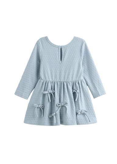A light blue long-sleeve baby dress with a textured waffle pattern, a keyhole neckline, and decorative tie bows on the skirt, shown against a plain white background.