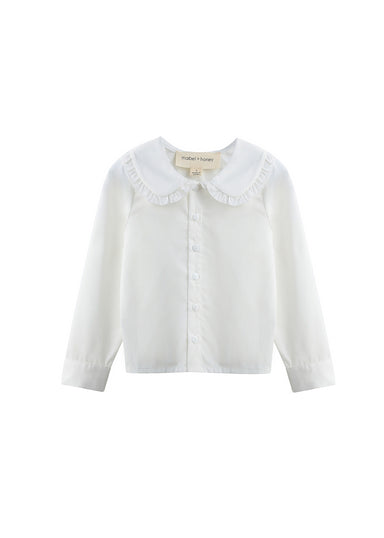 A white long-sleeve button-up blouse for children, featuring a wide ruffled Peter Pan collar and a small brand label at the inner neck, displayed on a clean white background.