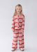 A young girl with blonde hair stands against a light gray studio background wearing a matching two-piece pajama set with a red and pink argyle pattern.