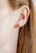 Football heart-shaped earrings worn by a person with long hair.