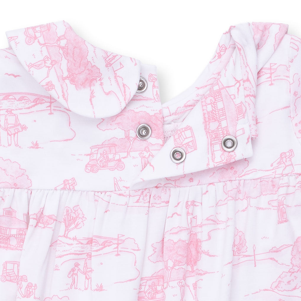 Close-up of a baby romper with pink and white toile pattern and button details.