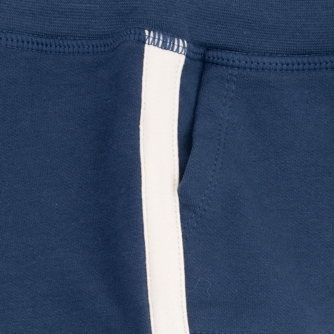 Close-up of a navy blue knit garment, likely sweatpants or a jacket, featuring a vertical white stripe running down the front.