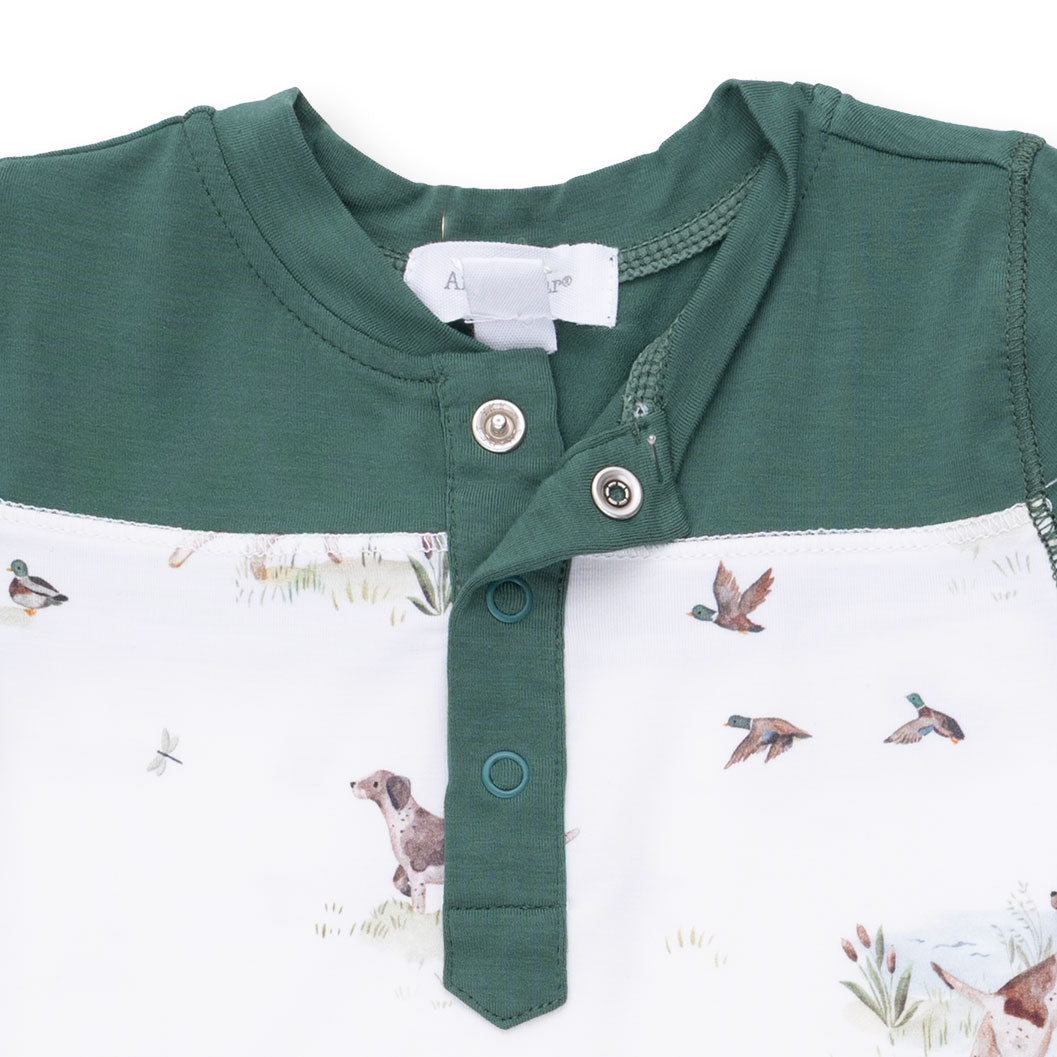 Green and white baby romper with dog and duck pattern on a white background