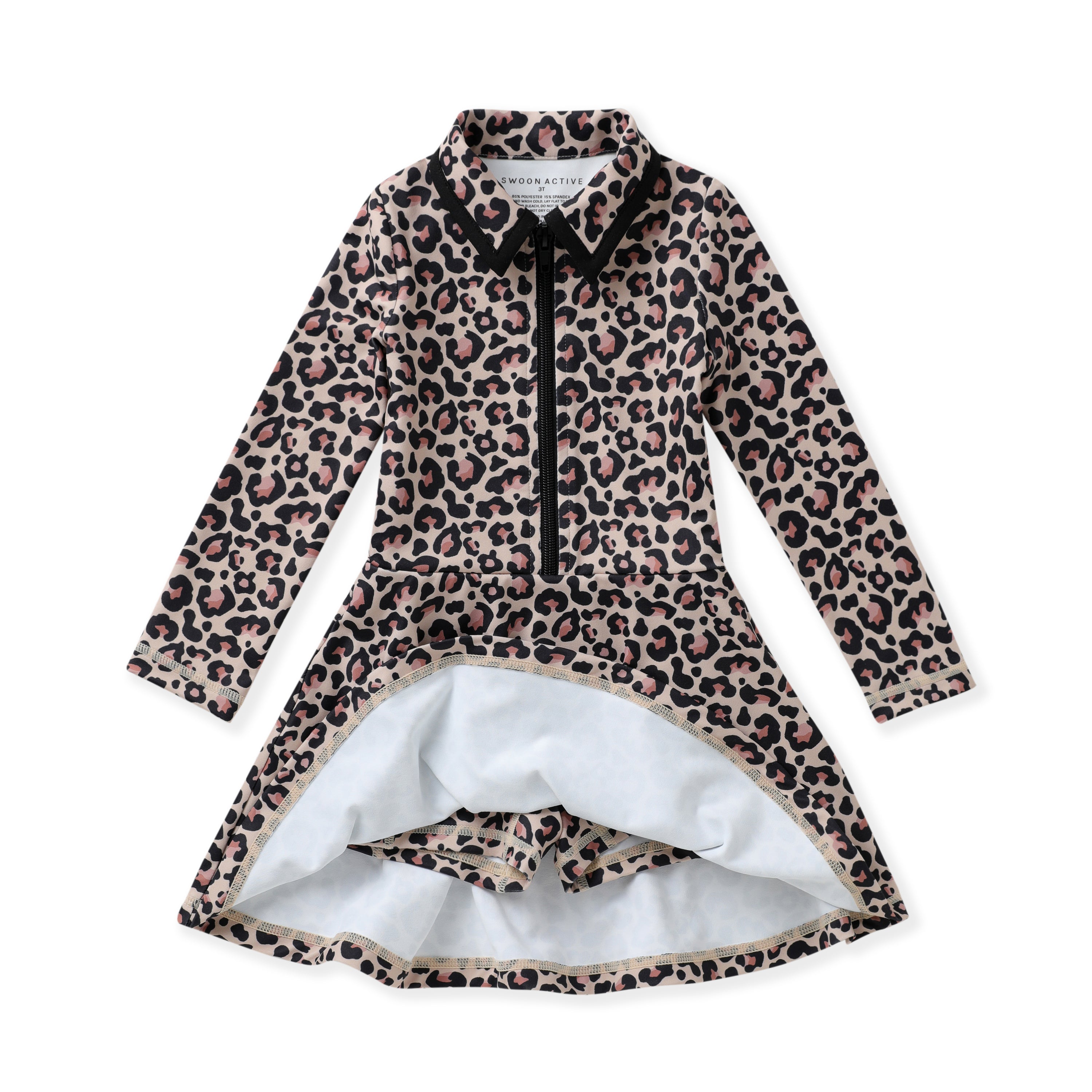 A long-sleeve collared tennis dress with a leopard print pattern in beige, brown, and black, featuring a black front zipper and a white inner lining visible at the split hem, with built-in shorts.