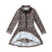 A long-sleeve collared tennis dress with a leopard print pattern in beige, brown, and black, featuring a black front zipper and a white inner lining visible at the split hem, with built-in shorts.
