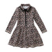 A long-sleeve girl's tennis dress with a leopard print pattern in beige, brown, and black, featuring a black collar, black tie detail at the neckline, and a black front zipper.