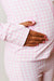 A close-up of a person wearing a pink and white gingham pajama set, with one hand resting on their stomach.