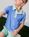 Child wearing a blue and green polo shirt with matching shorts on a grassy background