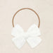 White bow headband on a beige background