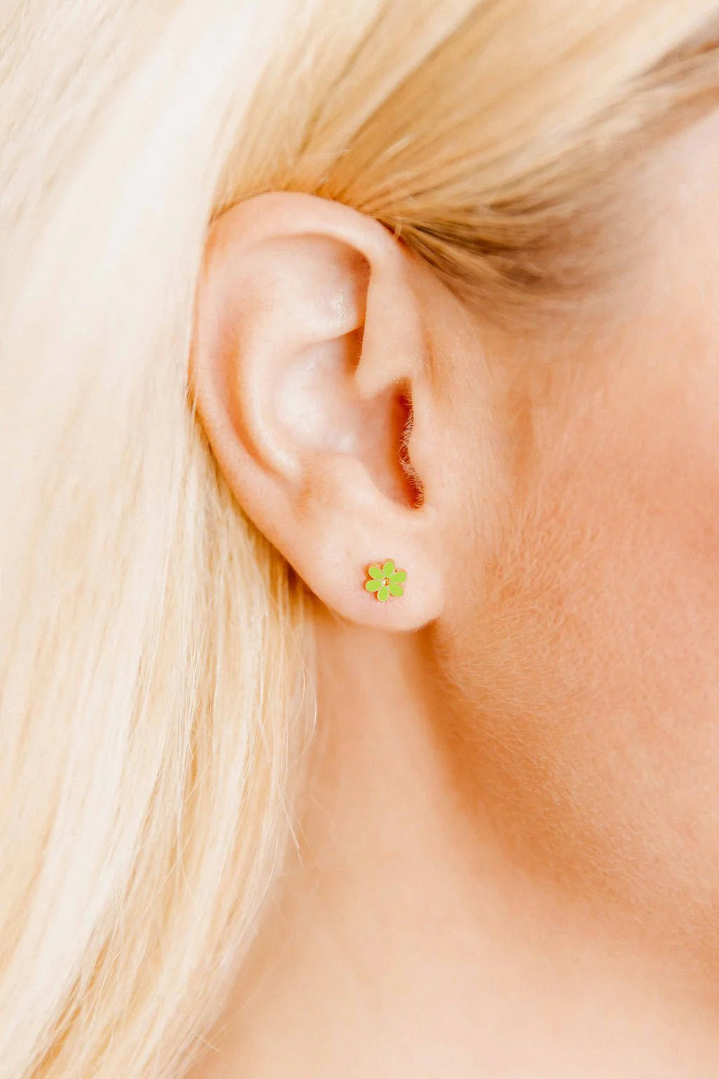 Close-up of a person wearing a green flower earring.