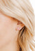 Close-up of a person wearing a small pink earring with a flower design.