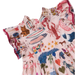 A close-up of a children's dress with a light pink base and a colorful all-over print featuring sea creatures, surfboards, stars, and animals. The dress has ruffled trim and is shown against a plain white background.