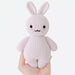 Knitted rabbit toy held in a hand against a white background