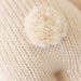 Close-up of a ball of cream-colored yarn on a textured beige surface.