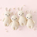 Four knitted bunny toys on a pink background