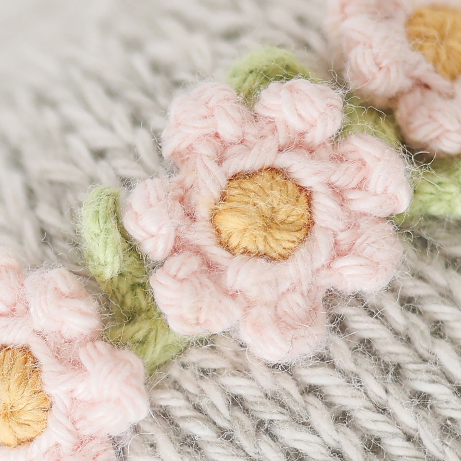 Close-up of pink crocheted flowers with yellow centers on a textured fabric background
