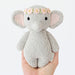 Knitted elephant toy with a flower crown held in a hand on a white background