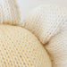 Close-up of three cream-colored yarn balls on a light background