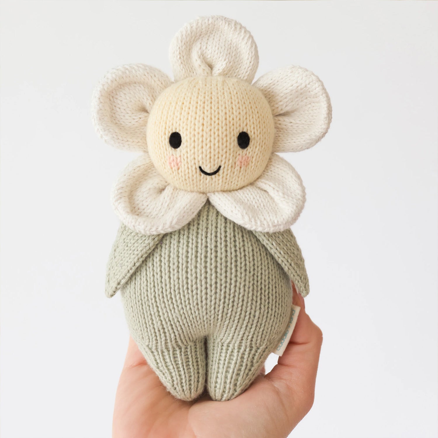 Knitted toy resembling a flower held in a hand against a light background
