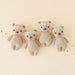 Four knitted teddy bears with floral headbands on a light beige background